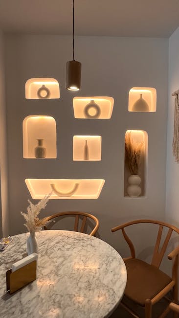 Apšviesta sienos niša su tvarkingomis lentynomis ir dėžutėmis