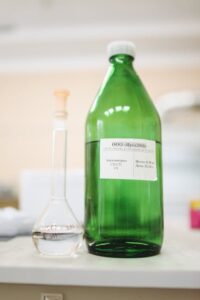 Žmogus skaito valymo priemonių etiketes, rinkdamasis mažiau cheminių medžiagų prieš renkantis valymo priemones.