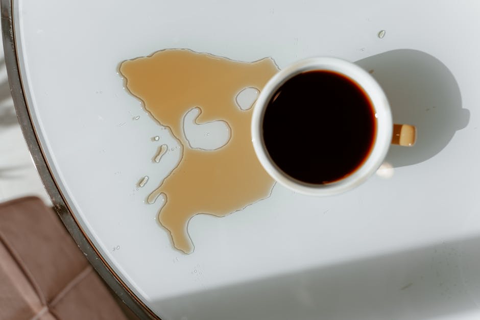 Išsiliejusi kava ant kilimo, žmogus sugeria dėmę popierine šluoste