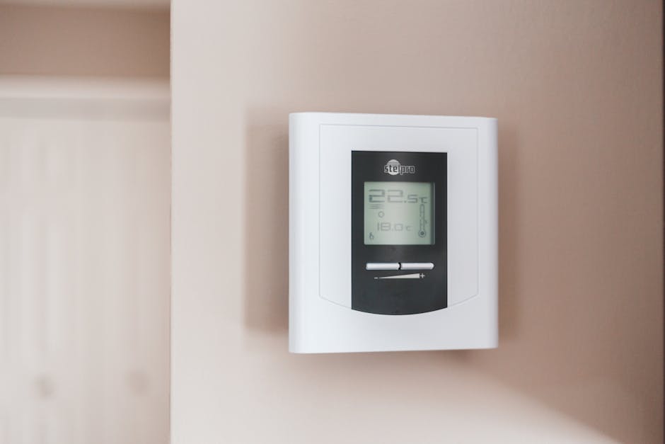 Virtuvėje ar katilinėje matomas boileris ir termostato valdymas, rodomas temperatūros nustatymas