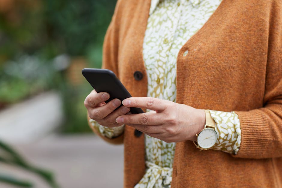 Žmogus lauke tikrina telefoną ir klauso radijo kieme